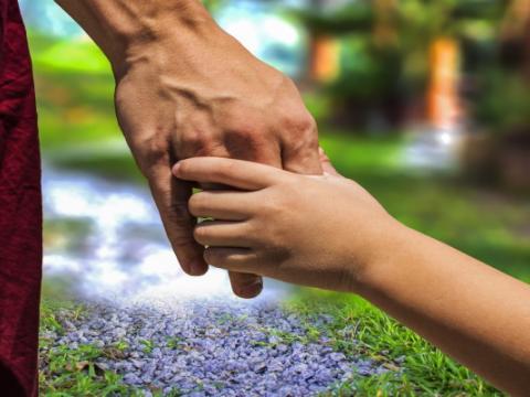 mano di adulto che tiene mano di minorenne