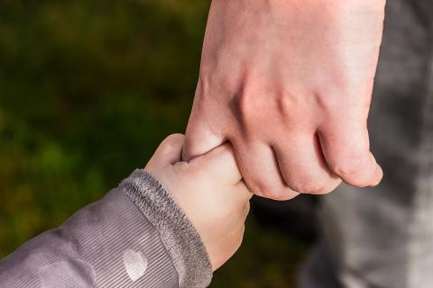 Mano di un bambino che stringe il dito di un adulto