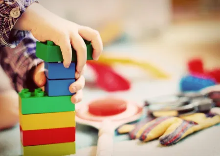 immagine con le mani di un bambìno che gioca con le costruzioni