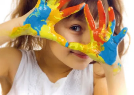 immagine di una bambina che mostra le mani imbrattate datanti colori