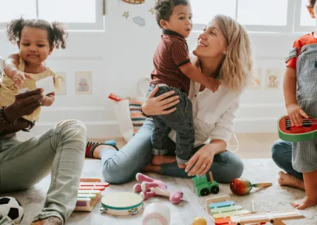 foto con una donna, seduta in mezzo a giochi sparsi sul pavimento, che stringe a se un bambino