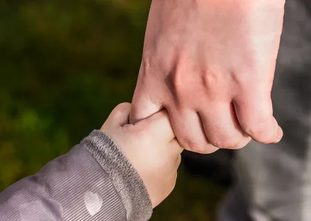 Mano di un bambino che stringe il dito di un adulto