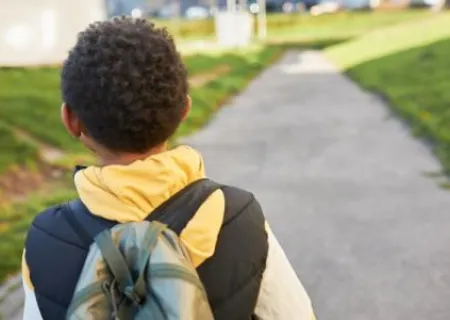 Bambino di spalle che pwercorre una strada