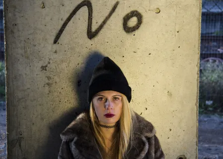 immagine con una ragazza con le spalle al muro sotto la scritta NO